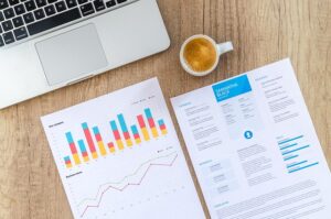 بيانات ومخططات وتقارير وتحليلات واحصاءات في اوراق امام حاسوب وكوب قهوة